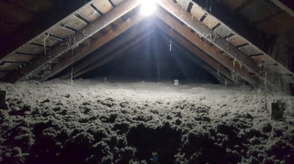 Cellulose insulation in progress in an attic